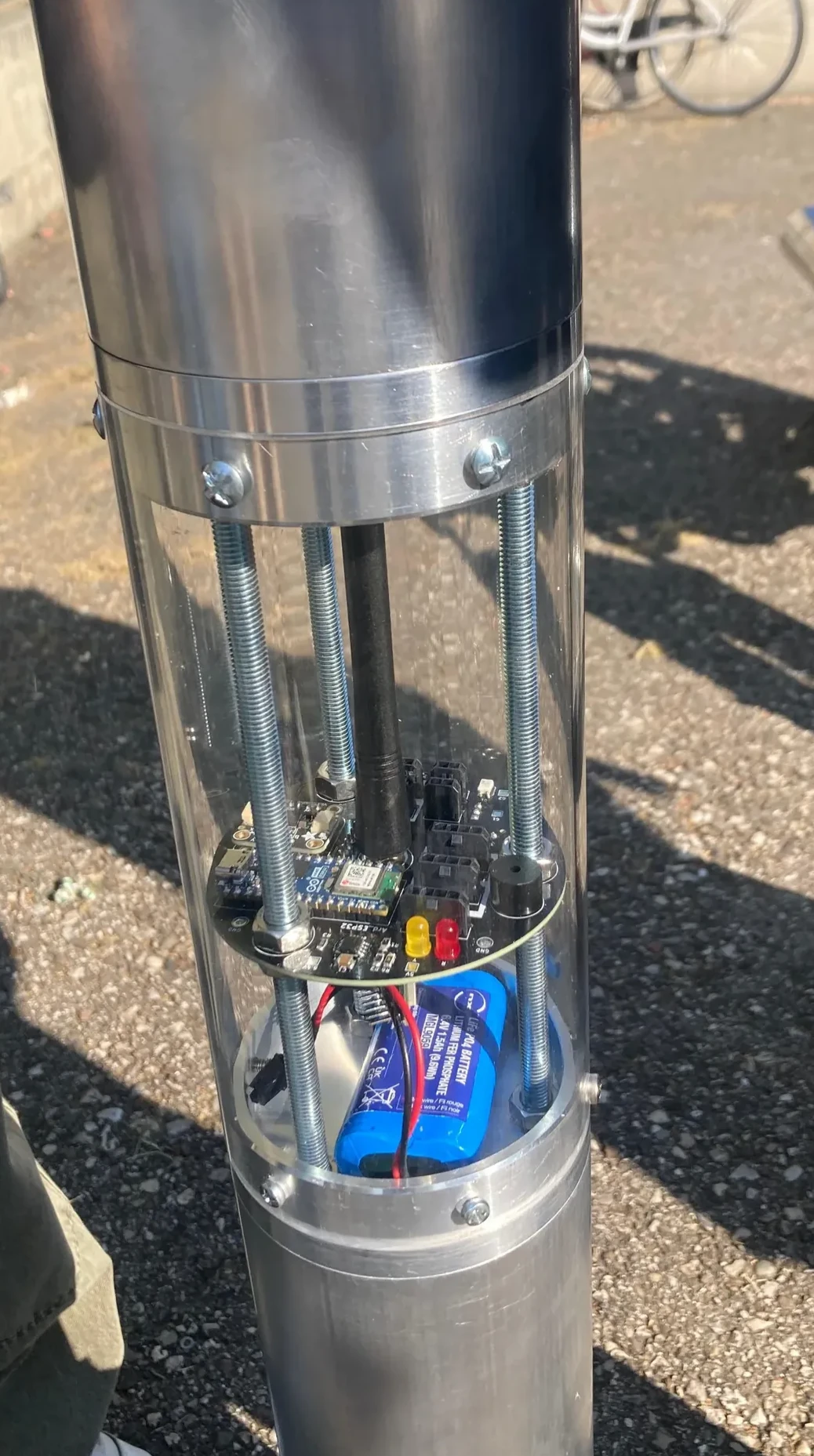 Rocket electronics bay with an onboard PCB, batteries, and wiring inside a transparent cylindrical enclosure